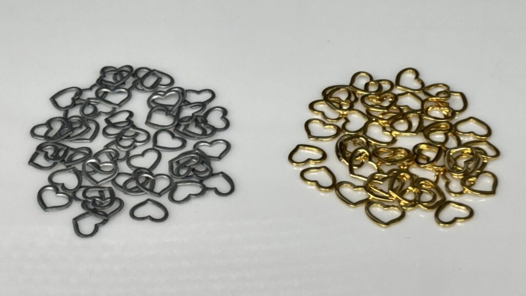 亜鉛合金の生地と金メッキ加工後のハート型パーツの比較